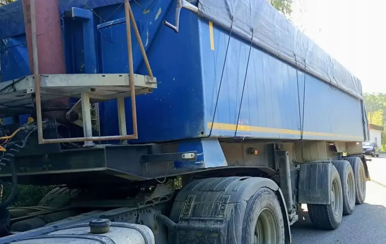 Niebieska naczepa z plandeką, widoczna od boku. Zastanawiasz się, ile waży ciągnik siodłowy? Ta potężna maszyna z pewnością sporo.