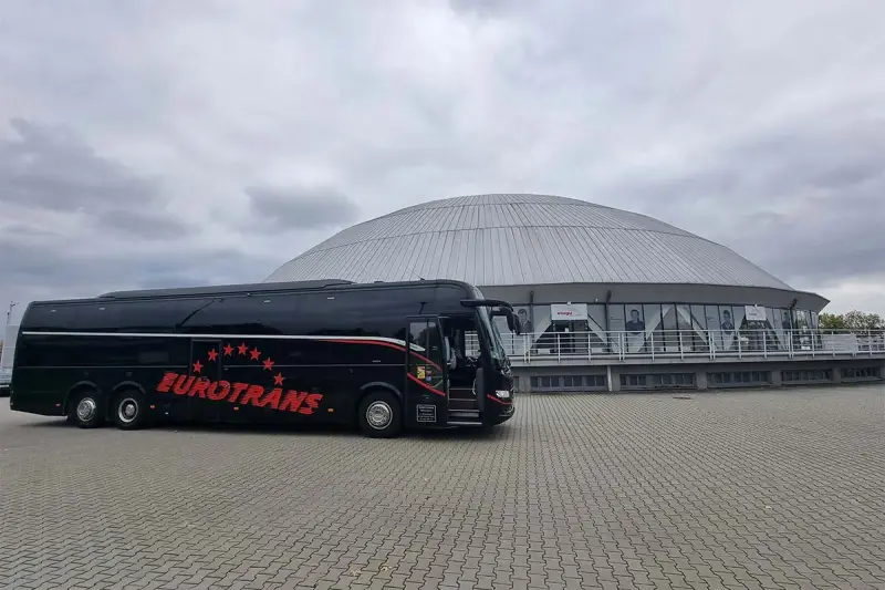 Czarny autokar Eurotrans z czerwonymi gwiazdami i napisem. Zastanawiasz się, ile miejsc ma autokar?